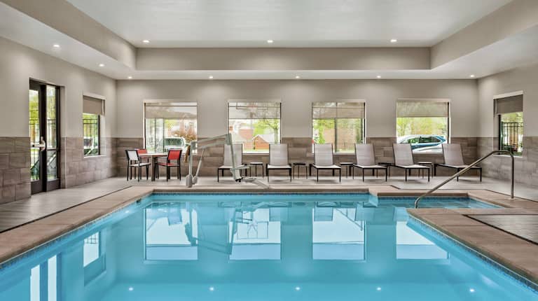 Spacious on-site indoor swimming pool featuring large windows, ample seating, and accessible chair-lift.