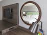 King Bed Reflected in Round Wall Mirror Above Work Desk in Guest Room with Wall-Mounted Flat Screen TV