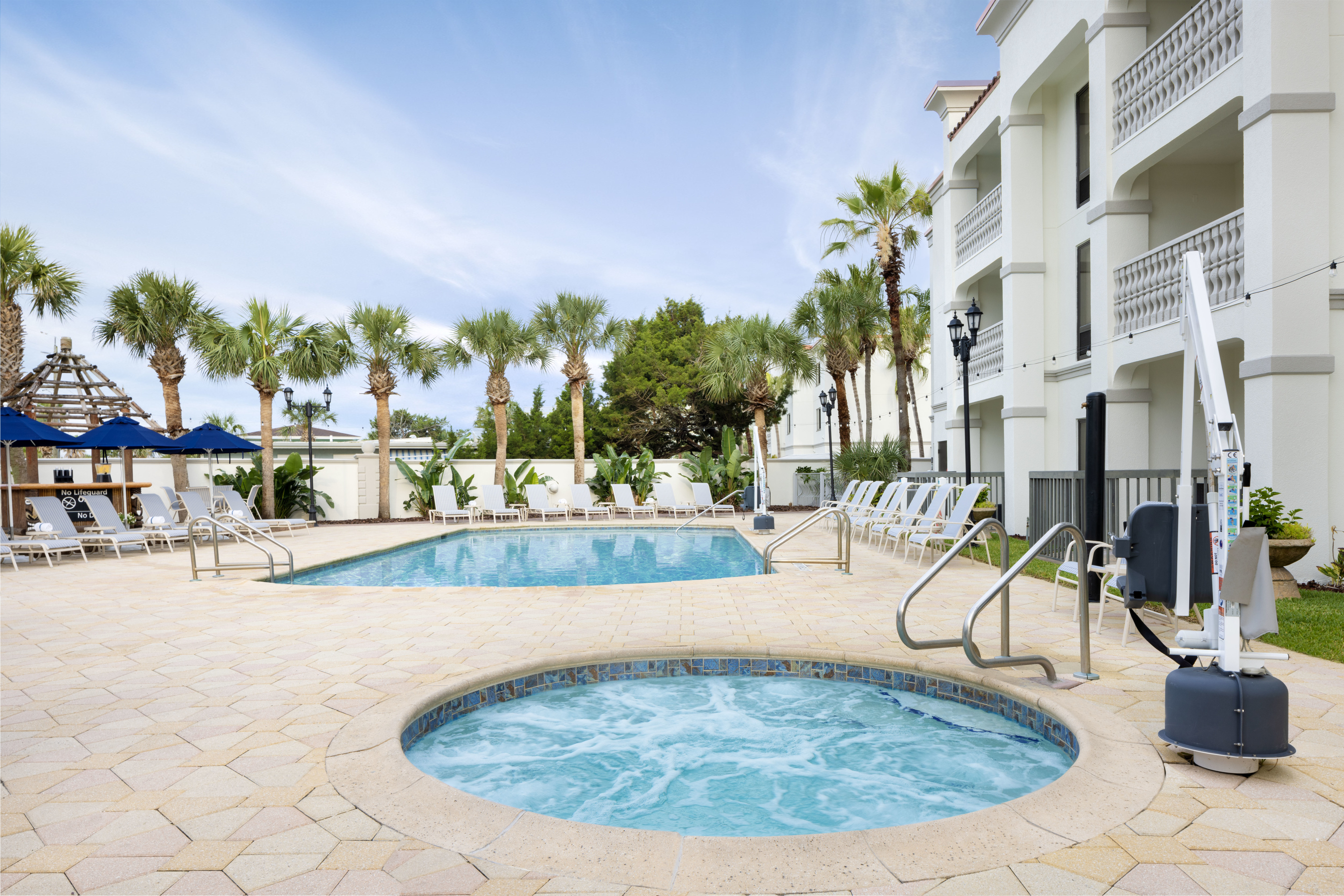 outdoor pool and hot tub, lounge chairs, palm trees, accessible lift
