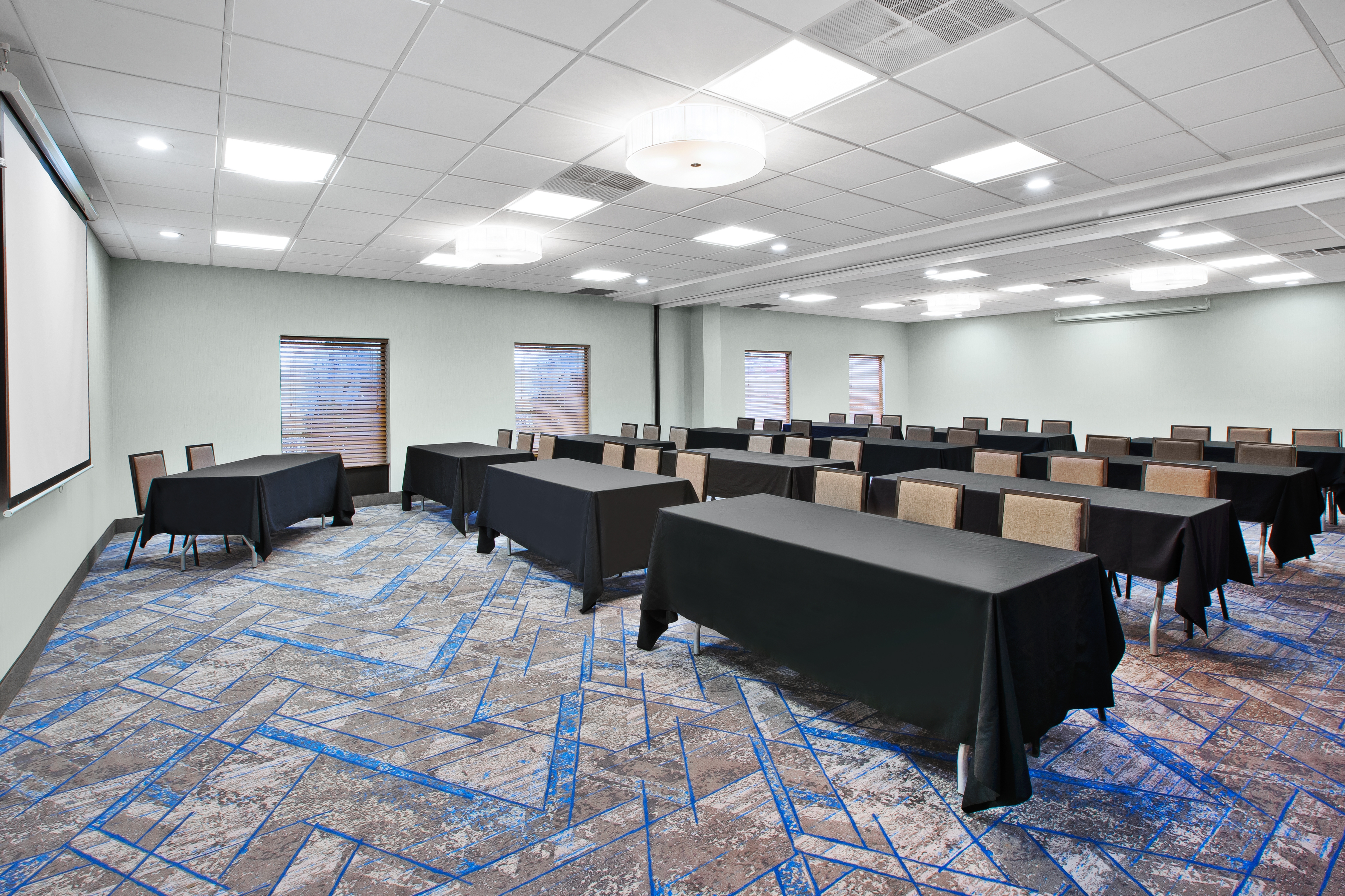 Meeting Room With Tables and Chairs in Classroom Style Setup and Projector Screen