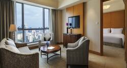 Guest Suite Lounge Area with Sofa, Armchairs, Coffee Table, City View and Wall Mounted HDTV
