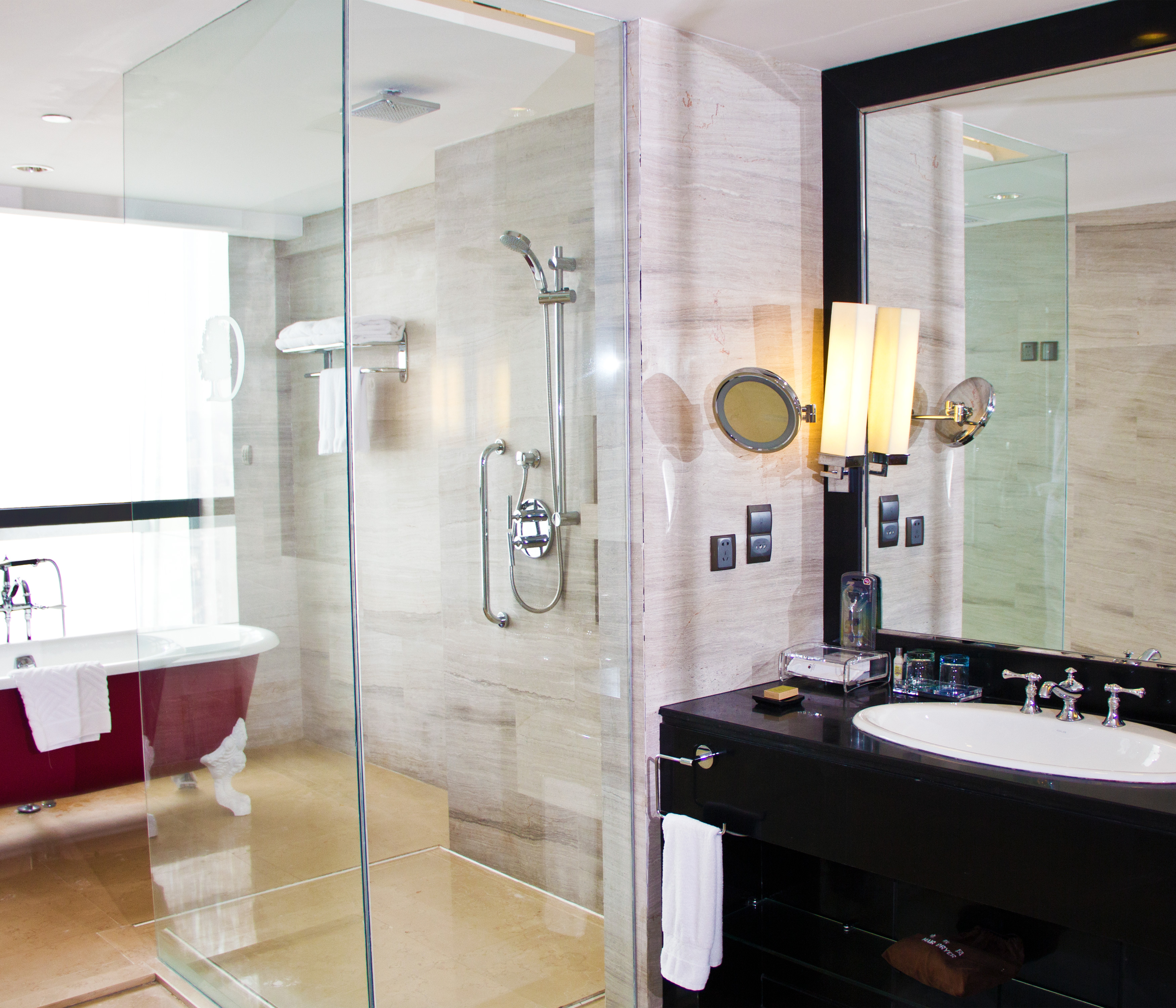 Executive suite bathroom with walk-in shower, tub, vanity mirror, sink, and towels
