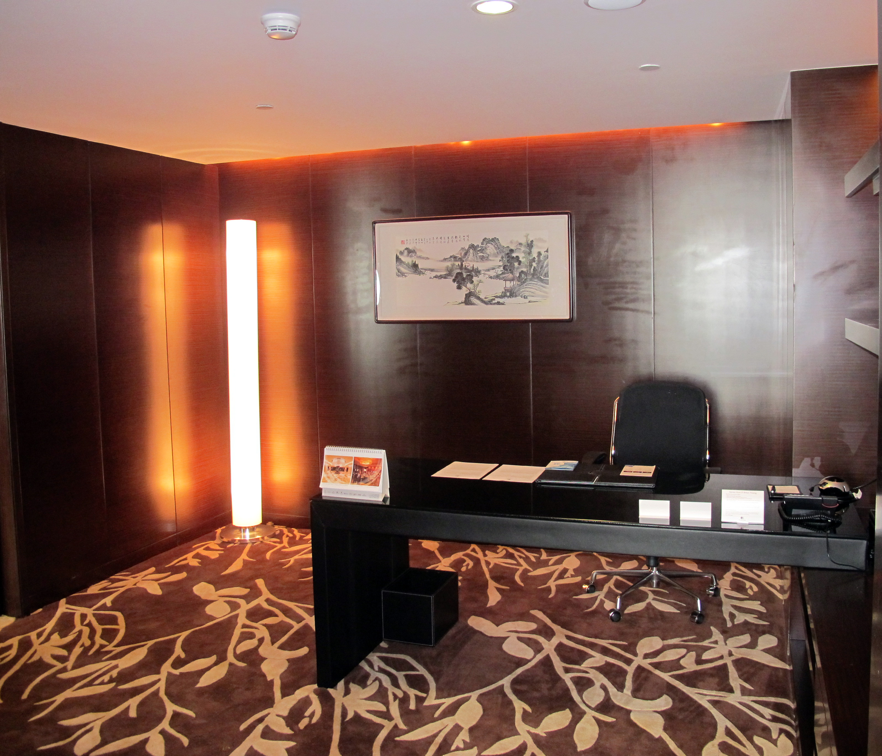 Presidential suite work desk with vertical illuminated floor lamp and art on the wall