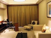 Superior suite living room with sofa, soft chair, ottoman, coffee table, and work desk