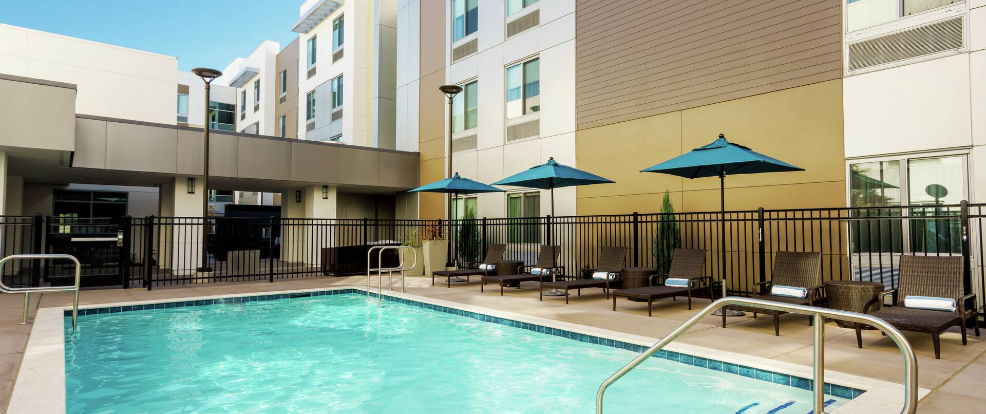 Outdoor Pool with Seating Along Side of Hotel