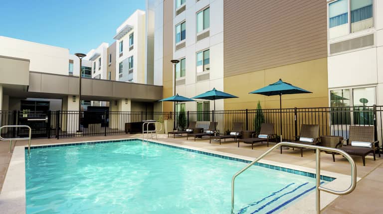 Outdoor Pool with Seating Along Side of Hotel