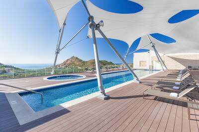 Outdoor pool with deck area and the ocean in the background