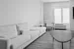 Guest room sitting area with a sofa, armchair, side table, and window blinds