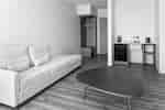 Guest room with a sofa, coffee table, open wardrobe, and coffee maker on a counter