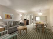 Spacious living area in suite featuring sofa, TV, dining table, and wet bar.