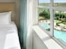 Bright bedroom in suite featuring beautiful view overlooking the large hotel pool, hot tub, and bar.