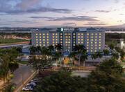 Ariel view of Embassy Suites by Hilton hotel surrounded by beautiful palm trees and sunset.