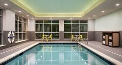 Beautiful large indoor pool featuring floor to ceiling windows, ample seating, and complimentary towels.