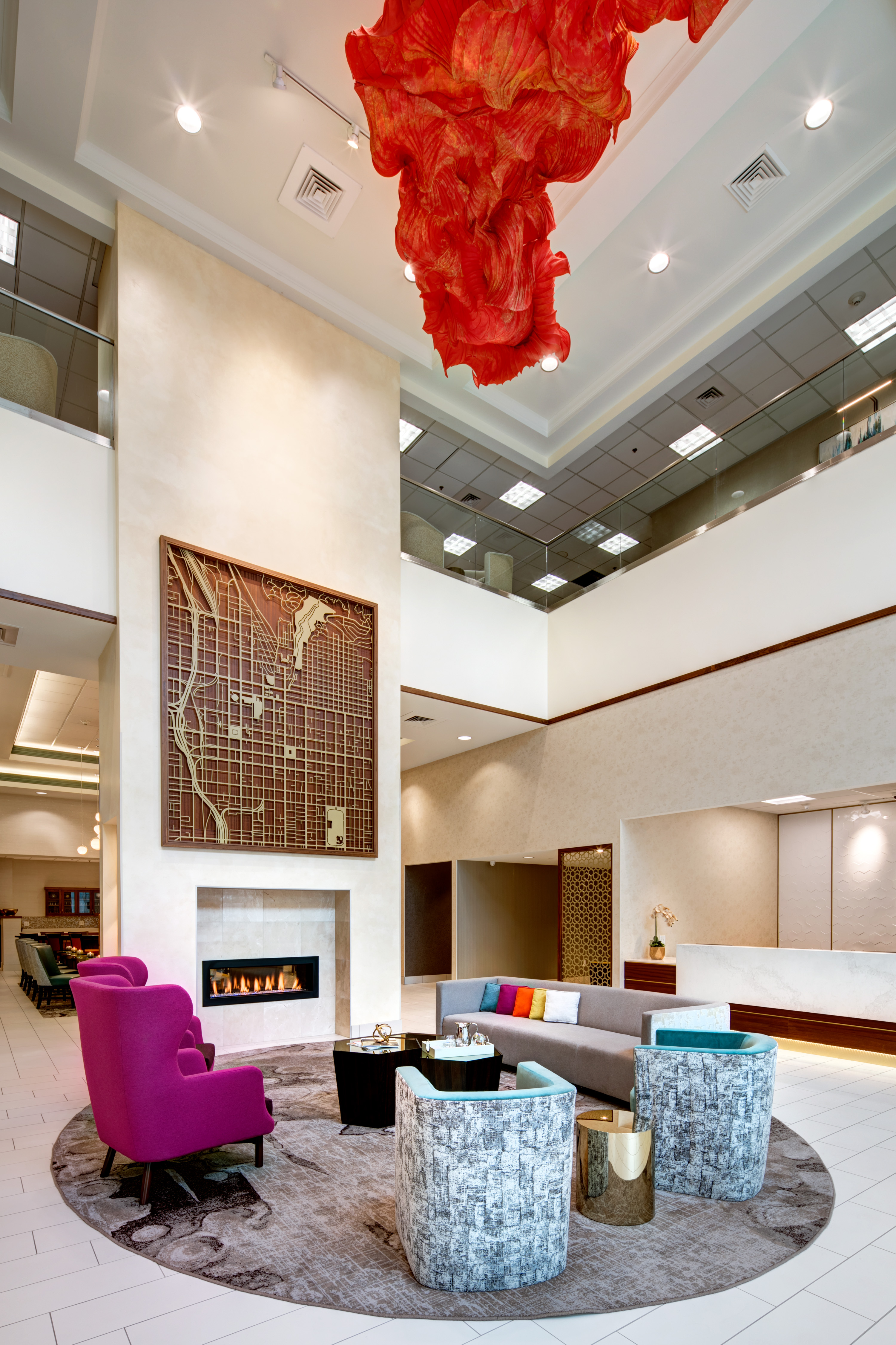 Atrium Seating With Fireplace, Art Feature Hanging From Ceiling, and View of Front Desk