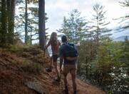 Couple Hiking on Wooded Hillside Next to Lake