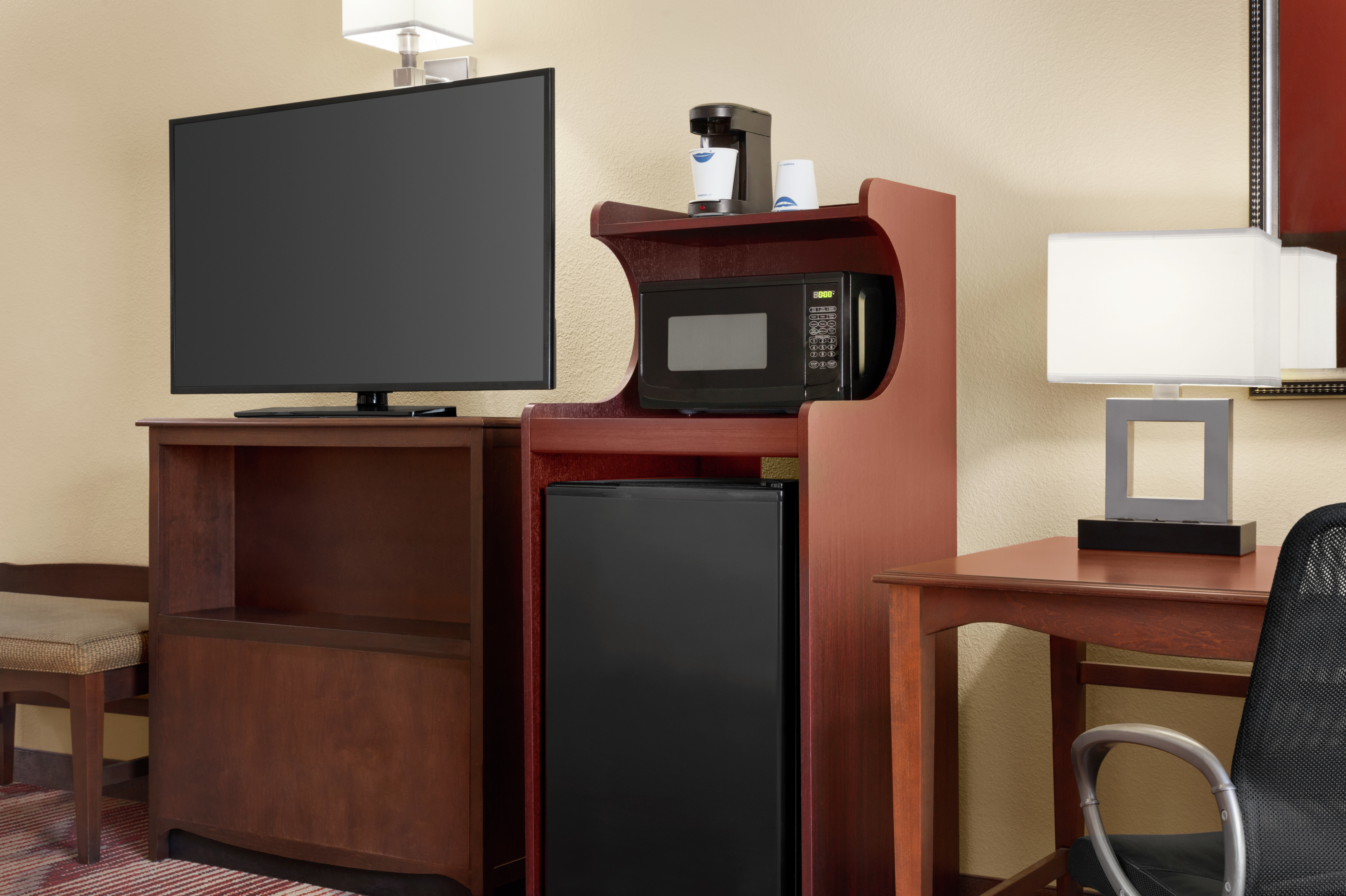 Bright accessible suite featuring work desk, mini-fridge, microwave, and TV.