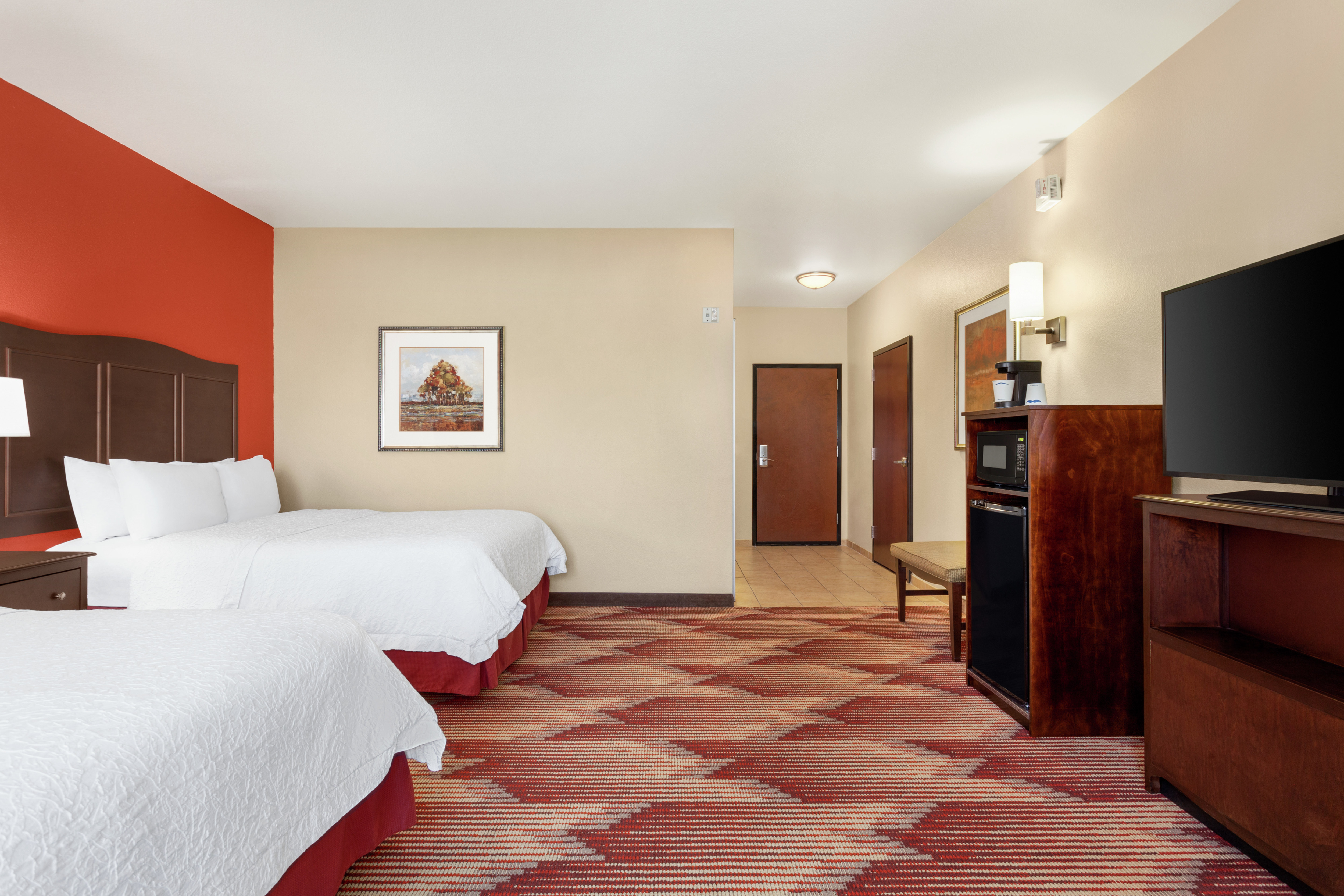 Spacious accessible guest room featuring two comfortable queen beds, TV, and mini-fridge.