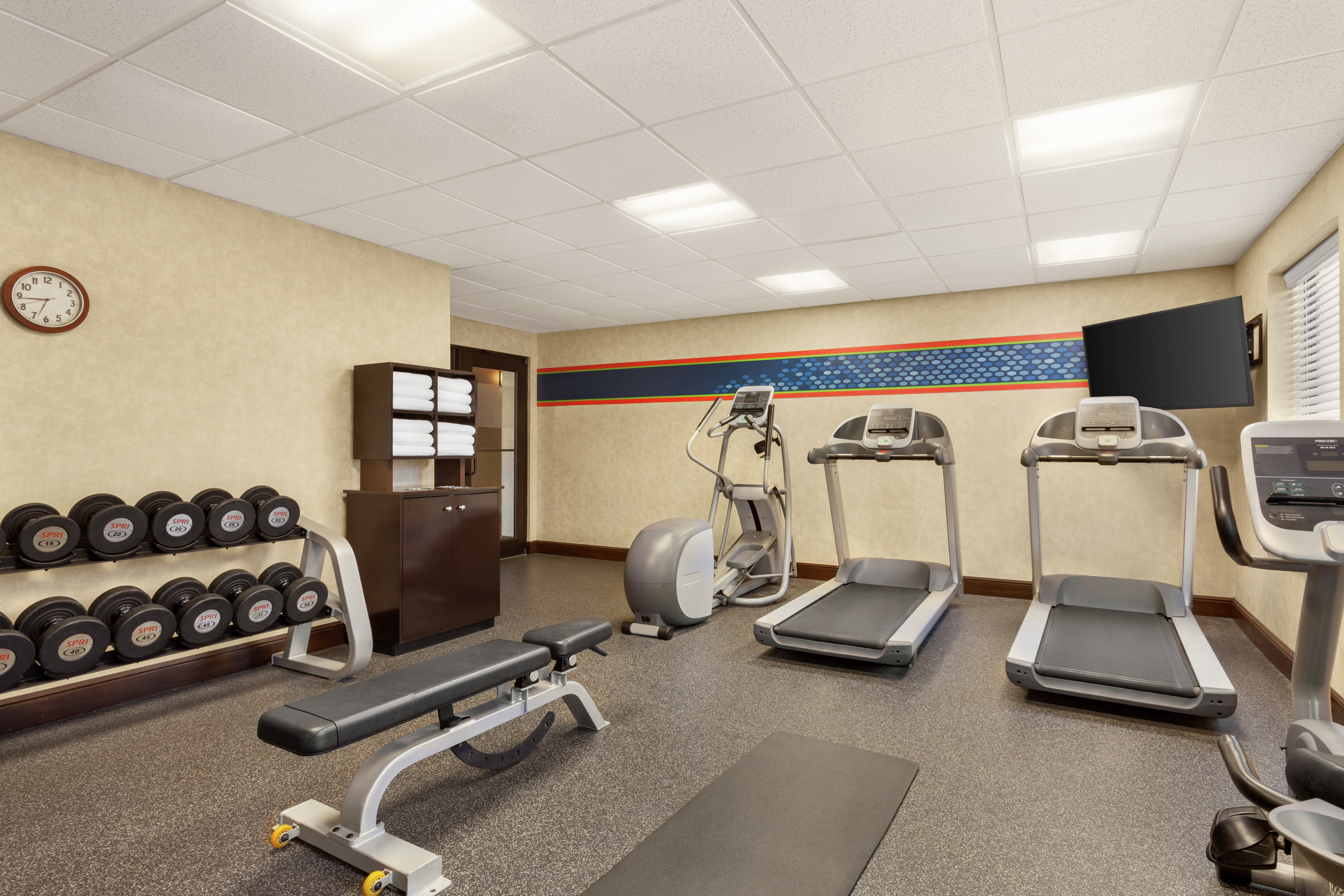 Convenient on-site fitness center featuring cardio machines, free weights, and TV.