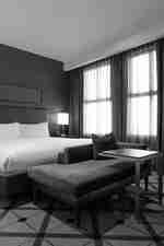 客房內的特大床，配以清新白色床單、紅色窗簾及紅色絲絨粗橫棱紋布料