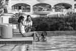 Man in swimming pool as two women relax at waters edge