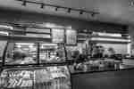 Coffee shop counter, cash register, and pastry case filled with various sweets & pastries