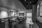 Moody coffee shop with tables, chairs, and artwork-lined walls