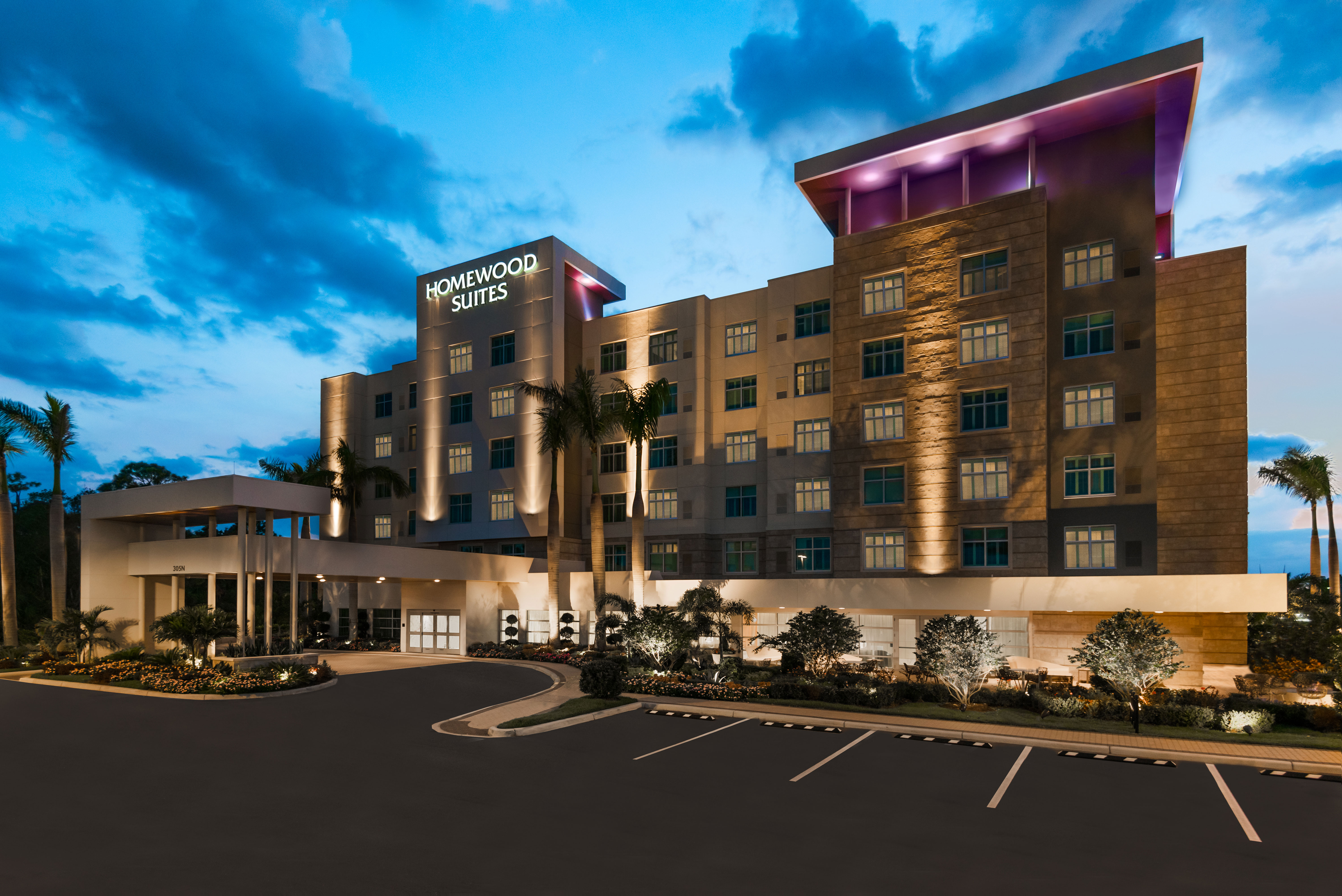 Angled View of Hotel Exterior, Signage, Landscaping, Circle Drive and Parking Lot Lit Up at Dusk