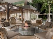 Night View of Outdoor Fire Pit Surrounded by Large Lounge Chairs and Tables with Umbrellas