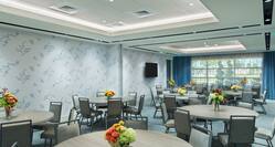 Meeting Room With TV, Seating at Round Tables with Floral Centerpieces, and an Outside View