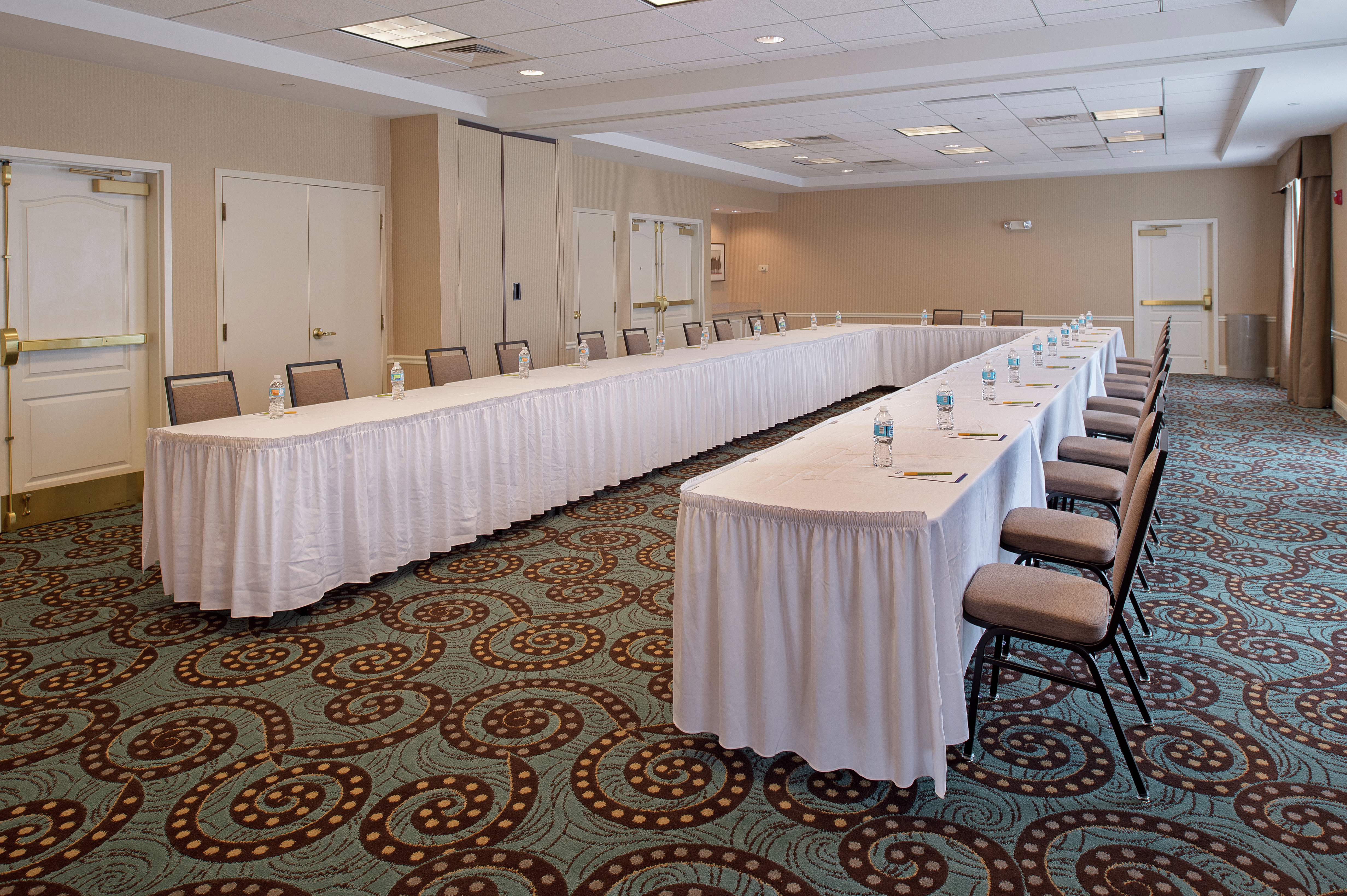 Meeting Room With U-Shaped Table, Chairs, Entry, and Windows WIth Long Drapes