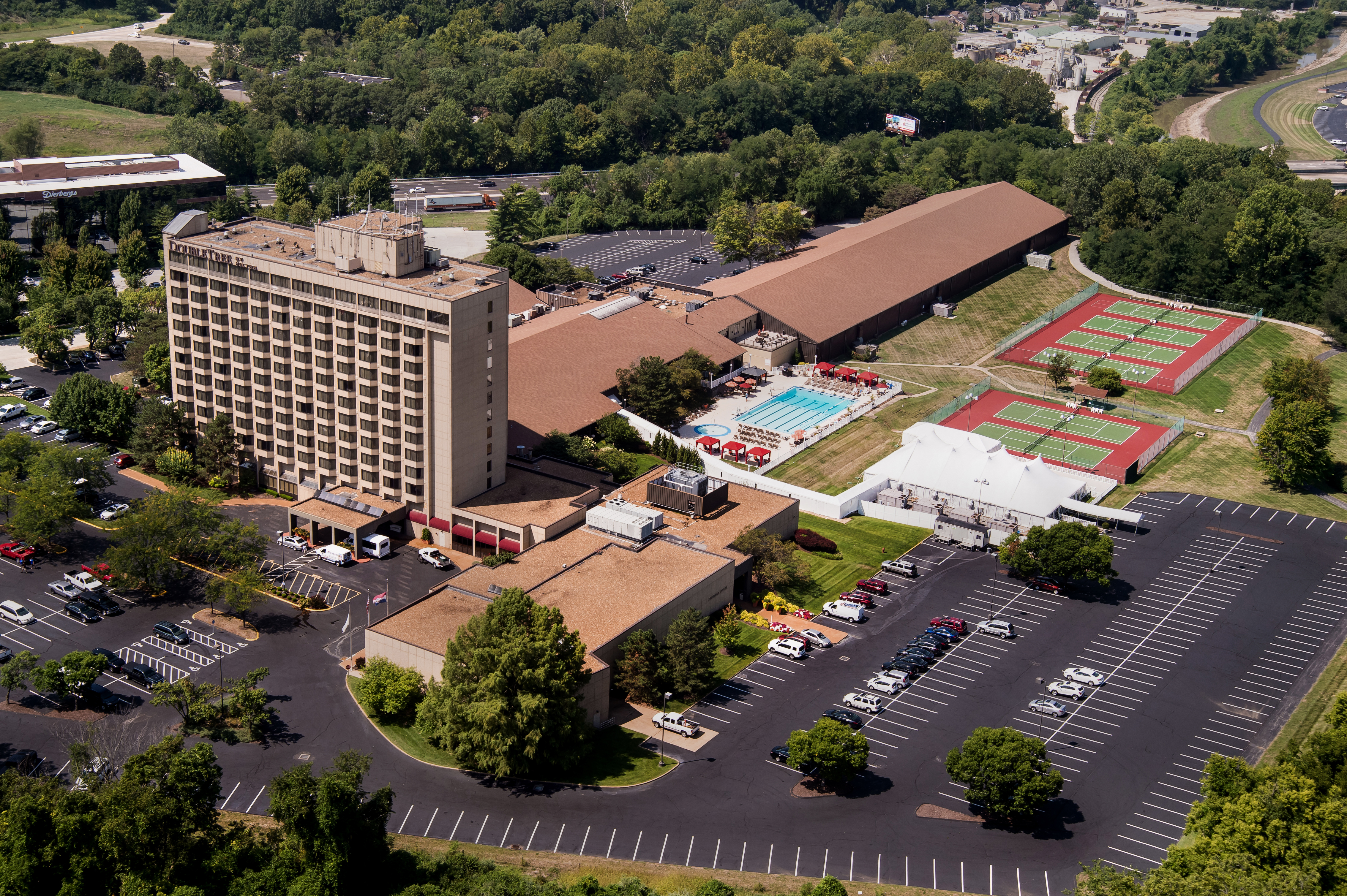 Overview of entire hotel property with athletic center, outdoor tennis courts, pool, and parking lot