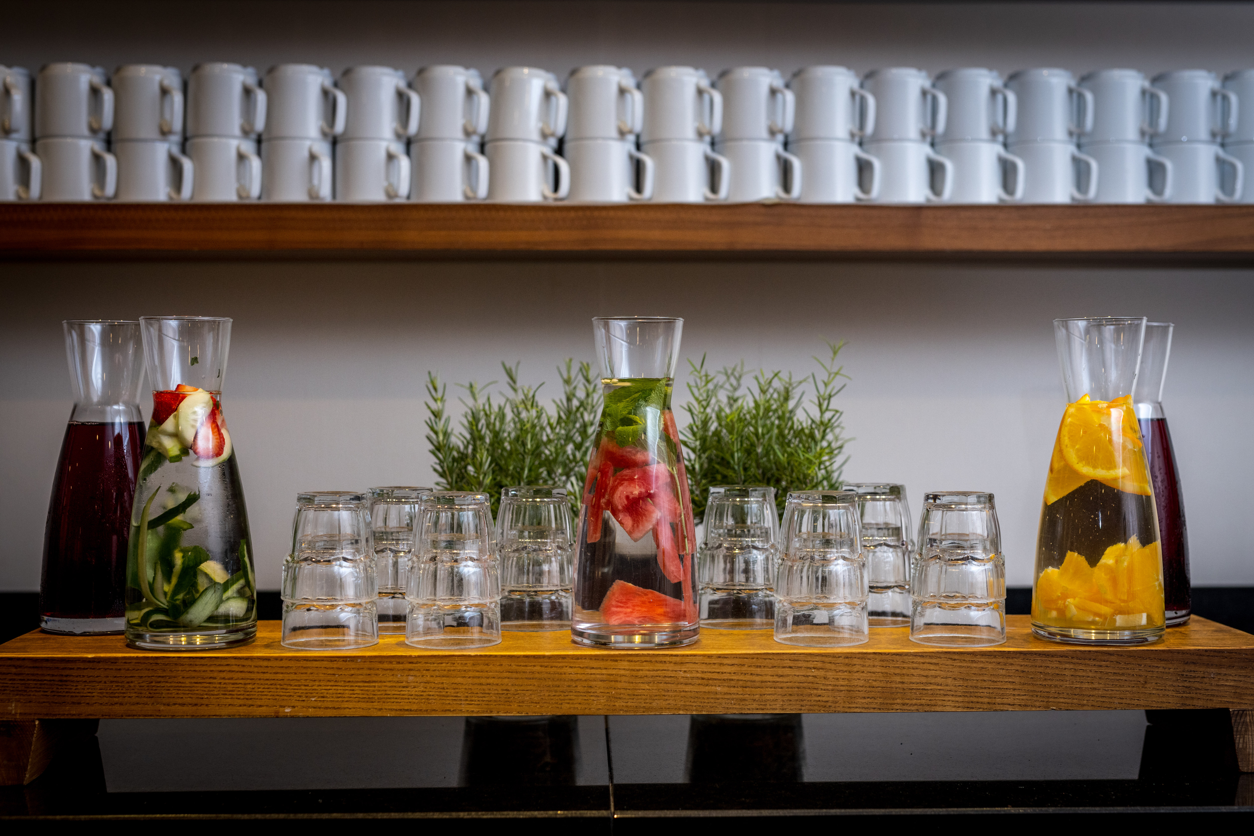 Aromatisches Wasser mit Gläsern und Tassen auf einem Tisch