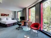 Bed, Desk and Chair by Floor-to-Ceiling Windows in Deluxe Room