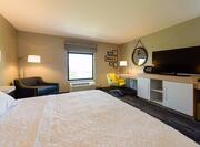 Accessible guest room with king bed, soft chair, work desk, TV, and window with outdoor view
