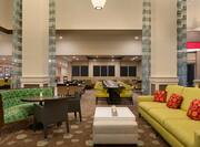 Lobby atrium with lounge sofas, coffee tables, and long dining table with chairs