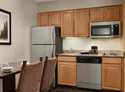 Spacious kitchen equipped with microwave, fridge, coffee maker, dishwasher, cook-top stove, and dining area.