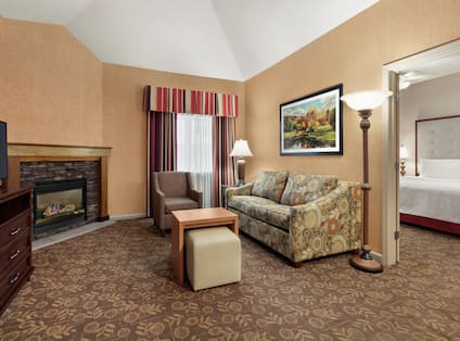 Spacious in suite living area with sofa, beautiful fireplace, TV, and private bedroom with comfortable king bed.