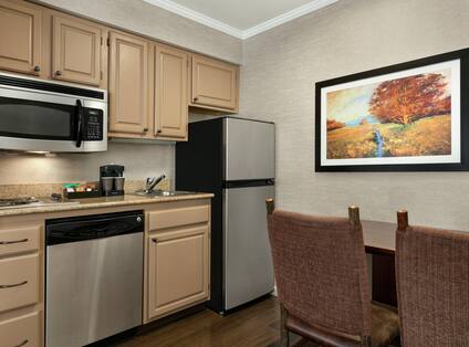 Spacious kitchen equipped with microwave, fridge, coffee maker, dishwasher, cook-top stove, and dining area.