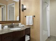 Spacious bathroom featuring vanity, large mirror, and combination shower and bathtub. 