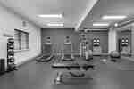 Spacious fitness center fully equipped with cardio machines, free weights, medicine balls, workout mats, and full length mirror.