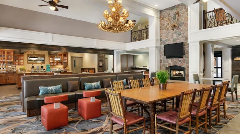 Spacious lodge area with rustic atmosphere featuring communal tables, chairs, fireplace, TV, and breakfast buffet.