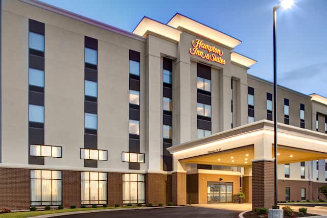 Front hotel exterior with circle drive under covered entrance, lit up at dusk