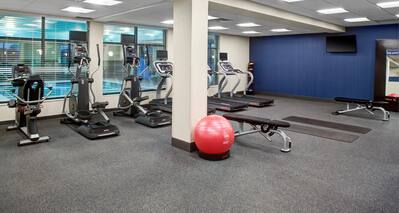 Fitness center with exercise machines and view of indoor pool through windows