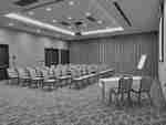 Meeting room with beige chairs set up in rows in front of a smart board 