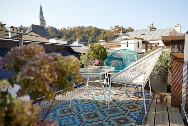 Private roof terrace with patio chairs, tables and flowers overlooking the old town
