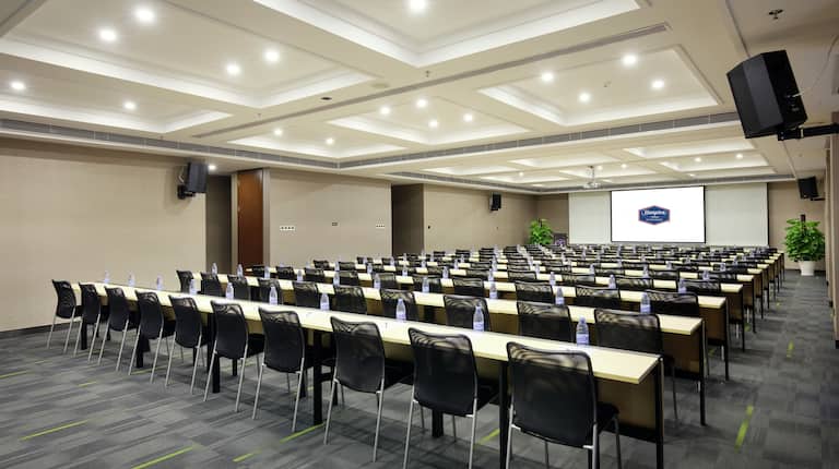 Meeting Space with Tables, Chairs, Speakers, and Projector Screen
