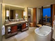 Executive suite bathroom with tub, vanity mirror, sink, towels, and outdoor balcony view