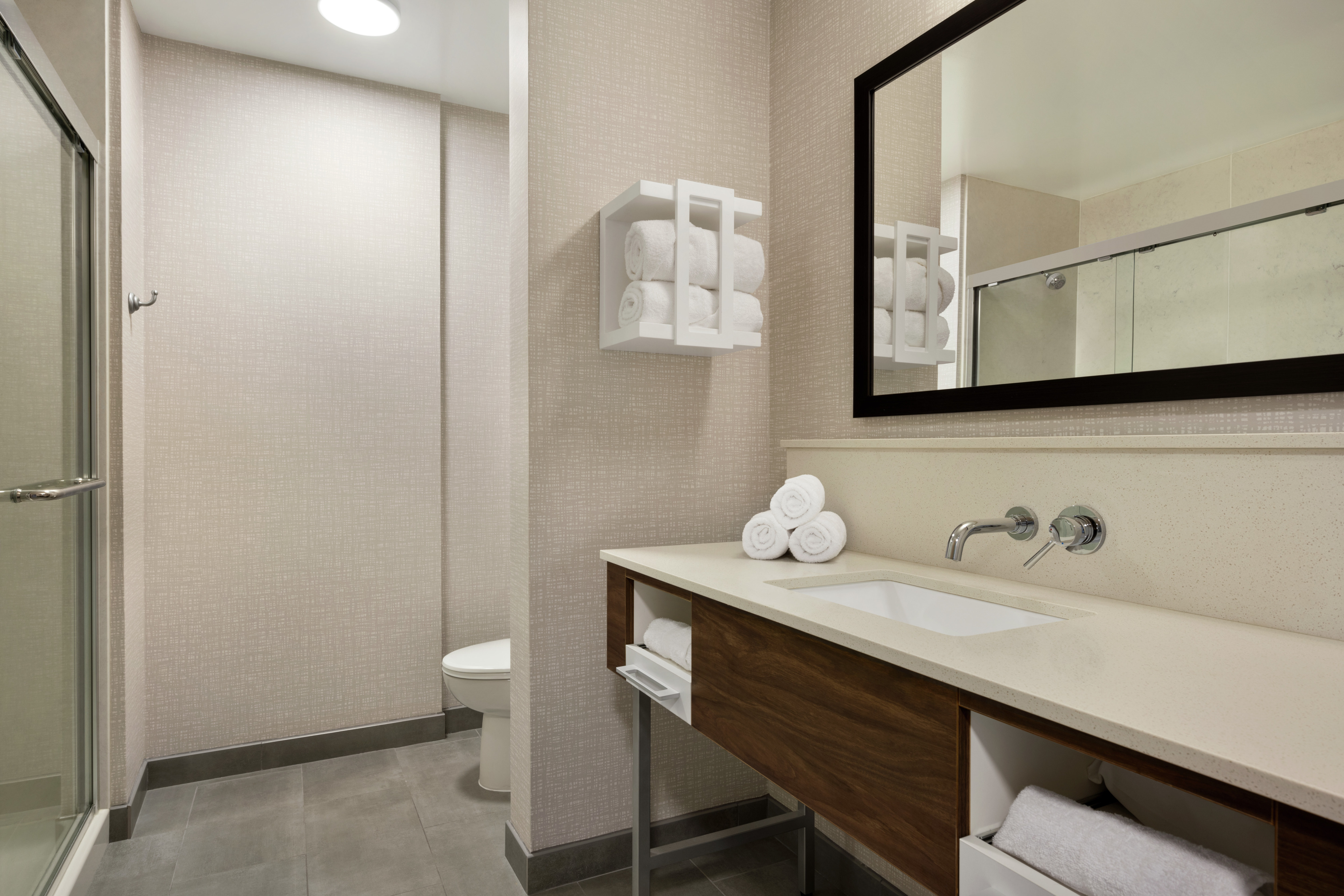 Spacious guest bathroom featuring walk-in shower with sliding glass door, large vanity, and mirror.