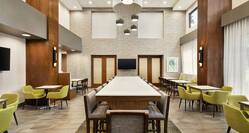 Spacious hotel lobby featuring high ceilings, ample seating, and large communal table.