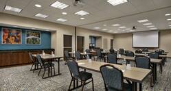 Spacious on-site meeting room featuring classroom setup, projector screen at front of room, and coffee break station.